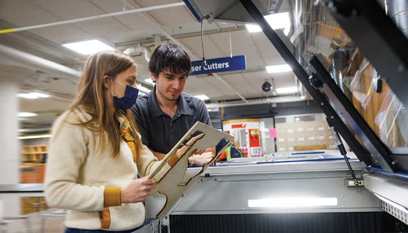 Two students use a laser cutter in think[box] on Case Western Reserve University’s campus.