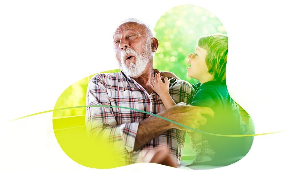 An elderly, bearded man pulls a face of mock surprise as their smiling grandkid jumps up at them.