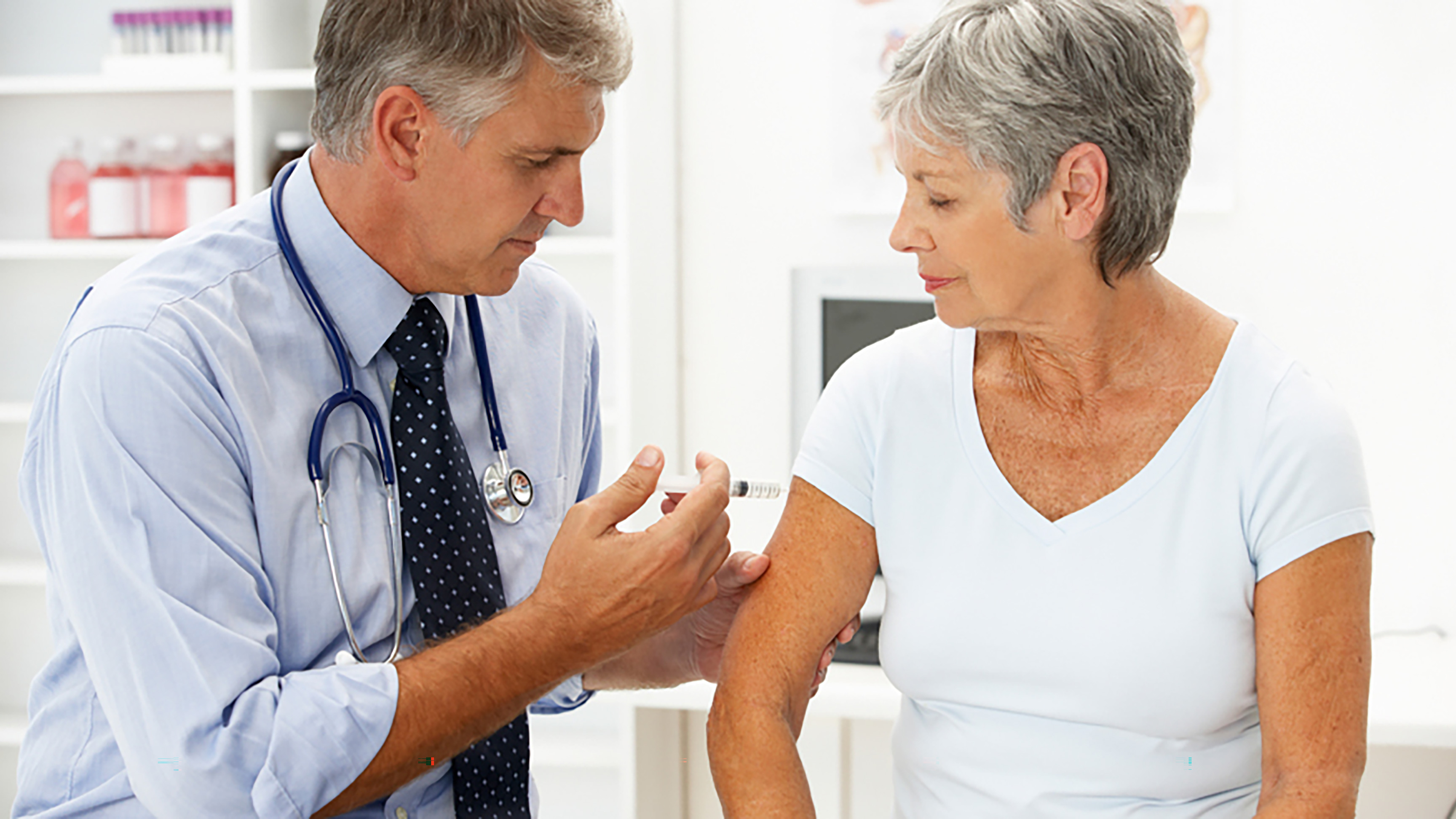 Image of male doctor giving vaccine shot to older female patient