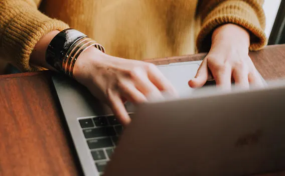 A woman's hands type on a laptop computer