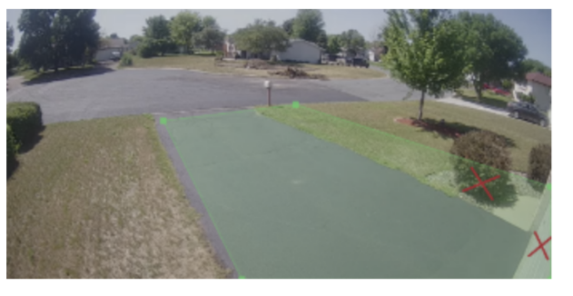 An outdoor camera's view of the driveway, and a green zone highlighted over the driveway and two X's showing where to not set the ground zone.