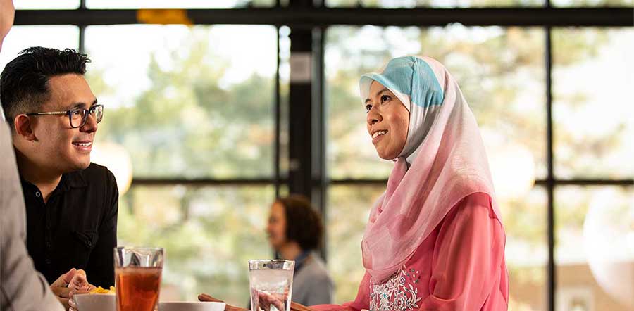 Twee mensen staan te praten aan een tafel 