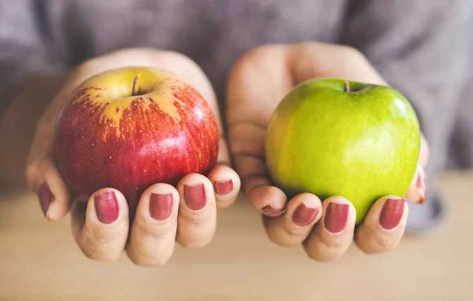 赤いリンゴと青いリンゴを持った手