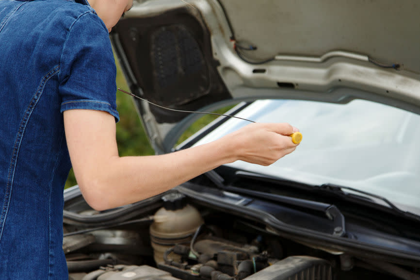 Franchigia assicurazione auto: giovane donna misura il livello dell’olio