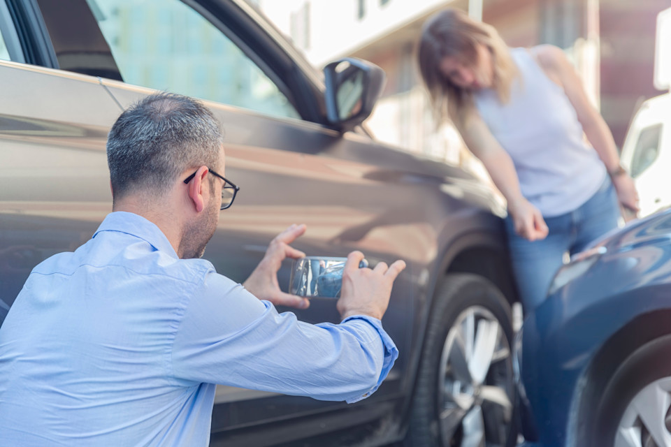 Mann steht vor beschädigtem Auto