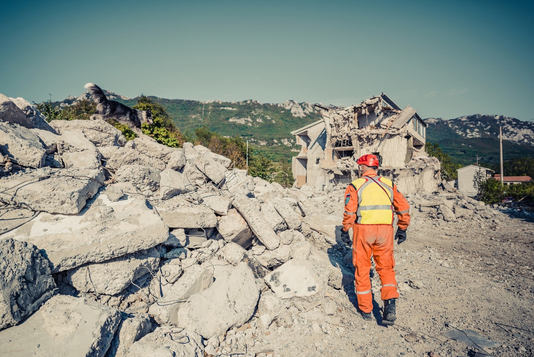Haushaltsversicherung Erdbeben: Mann und Hund durchsuchen zerstörtes Haus
