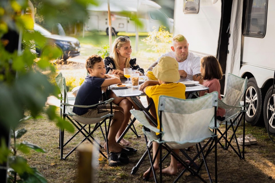 Familie neben dem Wohnwagen am essen.