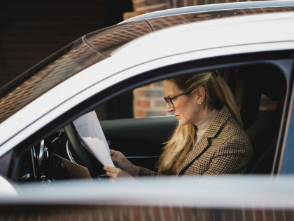 Autoversicherung kündigen: Frau mit Brief im Auto