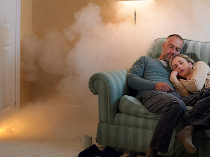 Selbstbehalt Haushaltsversicherung: Paar schläft auf Sofa, während Feuer ausbricht