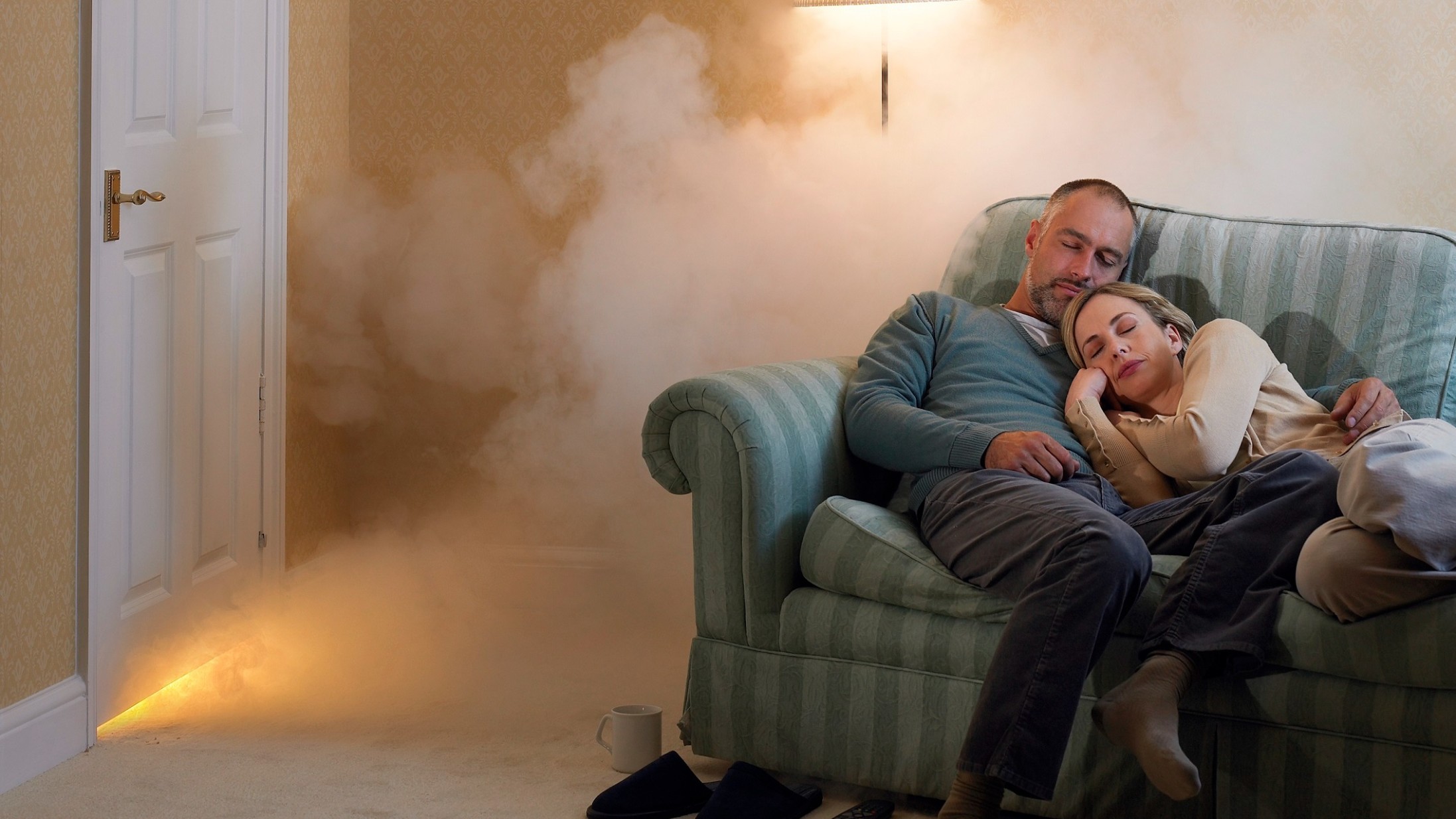 Selbstbehalt Haushaltsversicherung: Paar schläft auf Sofa, während Feuer ausbricht