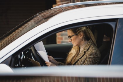 Autoversicherung kündigen: Frau mit Brief im Auto