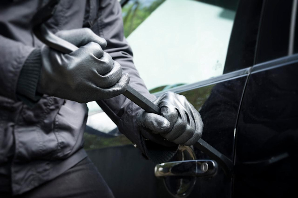 Person bricht Autotür auf.