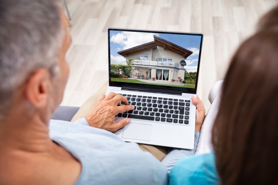 Mann und Frau betrachten ein Haus am Laptop