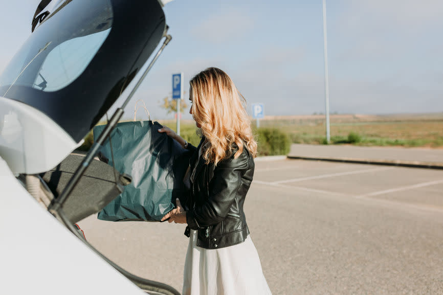 Unterlagen Motorfahrzeugversicherung: Frau lädt Einkaufstasche in Kofferraum
