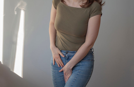 Frau hält eine Hand in ihren Intimbereich.