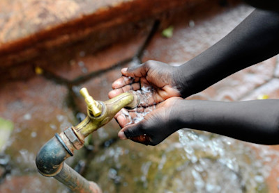 Kinderhände sammeln Wasser zum Trinken.