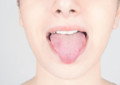 Ein weiblicher Mund streckt die Zunge heraus.