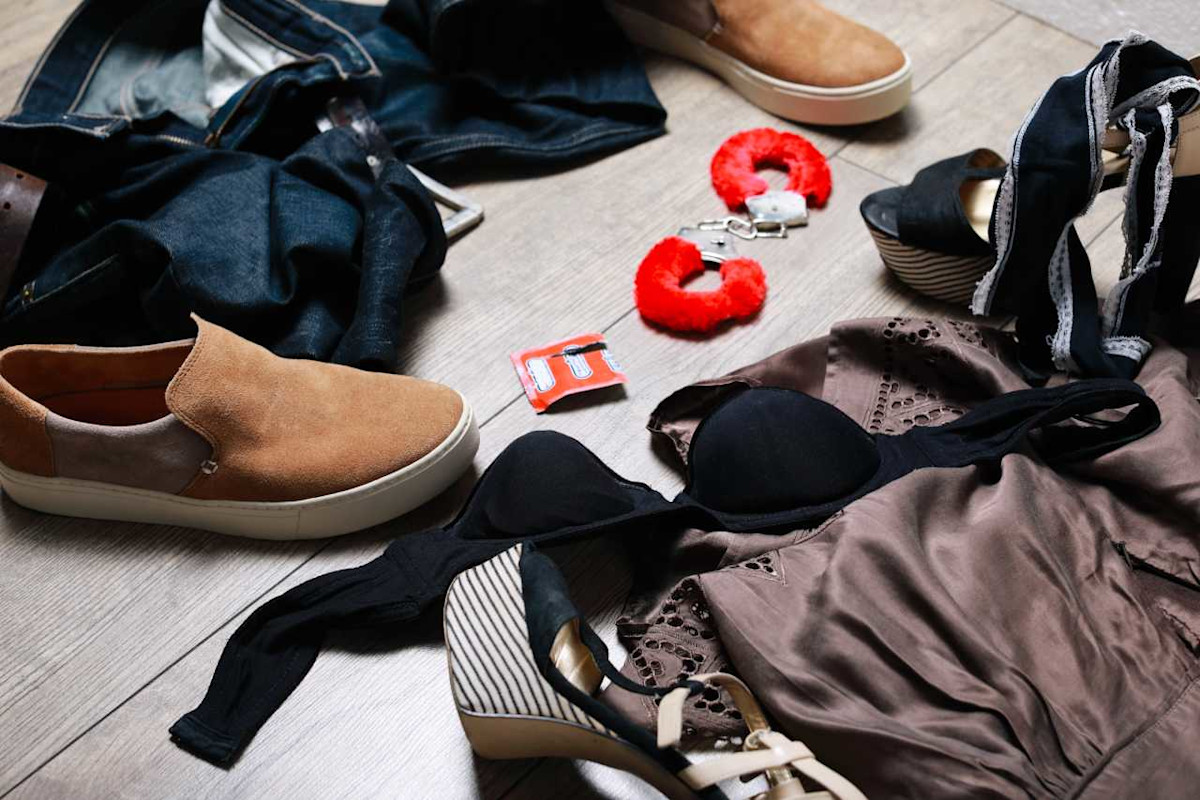 Auf dem Fußboden liegt Bekleidung von Mann und Frau. Außerdem eine Kondom-Verpackung und Handschellen.
