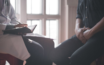 Mann mit Geschlechtskrankheit (STI) beim Arzt im Aufklärungsgespräch