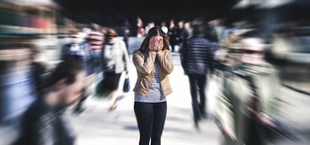 Frau hat inmitten einer Menschenmenge eine Panikattacke.