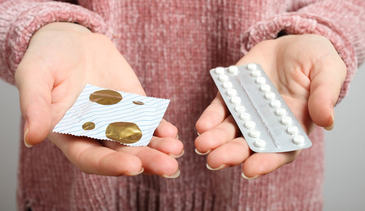 Welche Verhütungsmittel und Verhütungsmethoden gibt es? Eine Frau hält die Antibabypille und ein Kondom in ihren Händen.