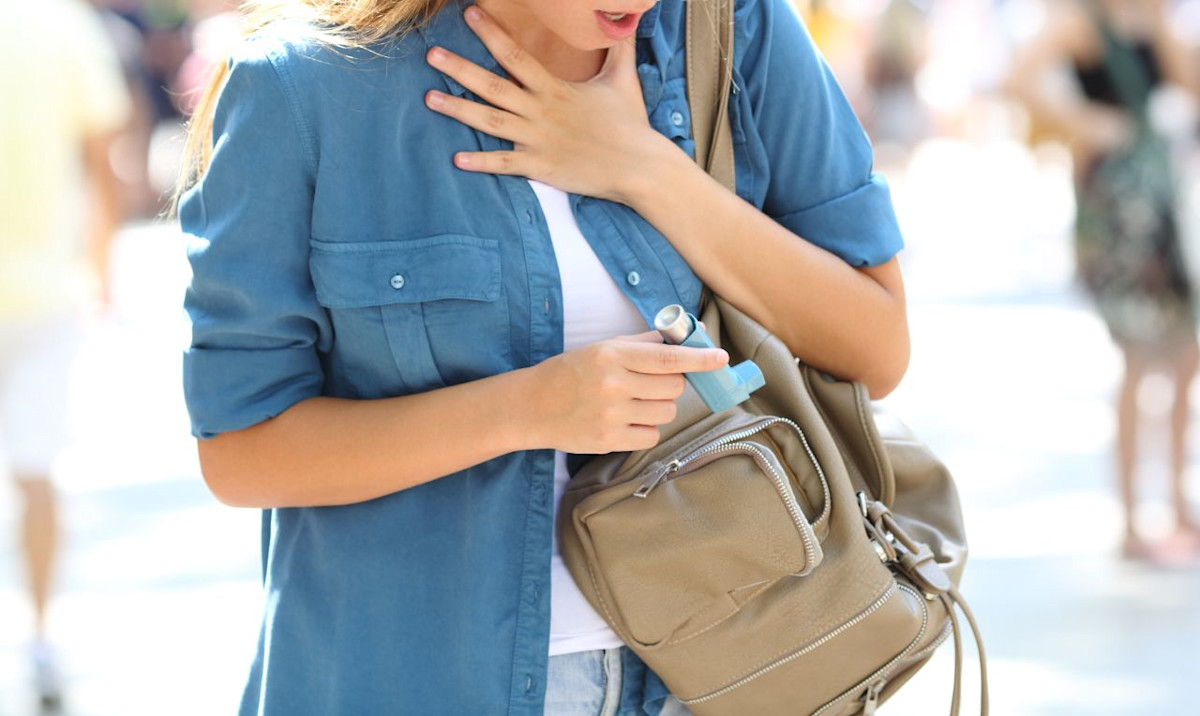 Frau holt Asthmaspray aus ihrer Tasche.