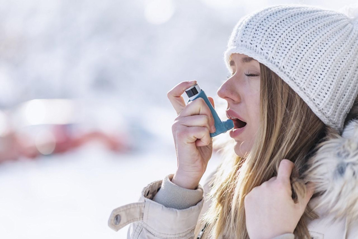 Junge Frau benutzt im Winter einen Asthma-Inhalator.