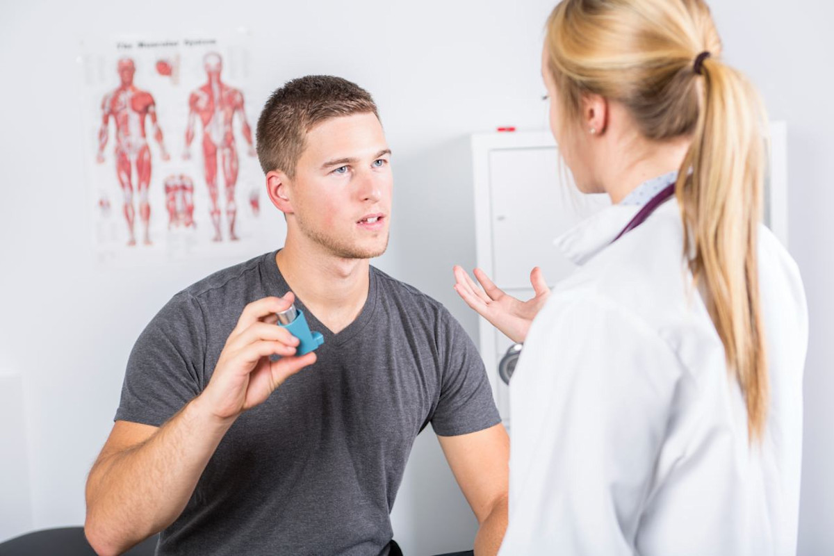 Ein Patient hält ein Asthmaspray in der Hand und redet mit einer Ärztin.