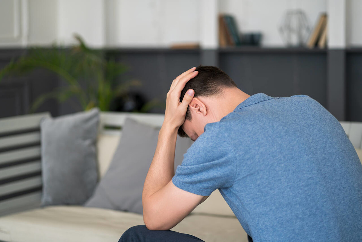 Ein Mann hält sich den Kopf.