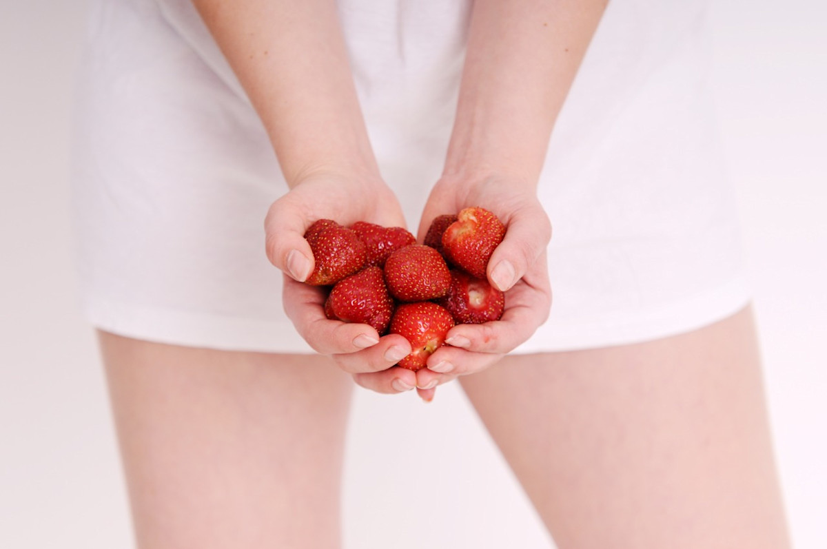 Frau hält Erdbeeren in der Hand.