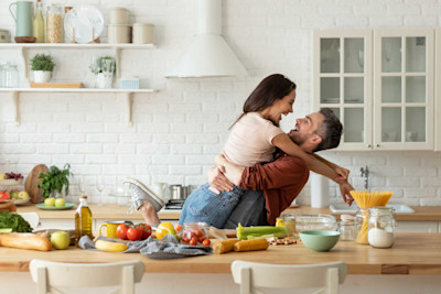 Ein junges Paar albert beim Zubereiten von Essen in der Küche rum.