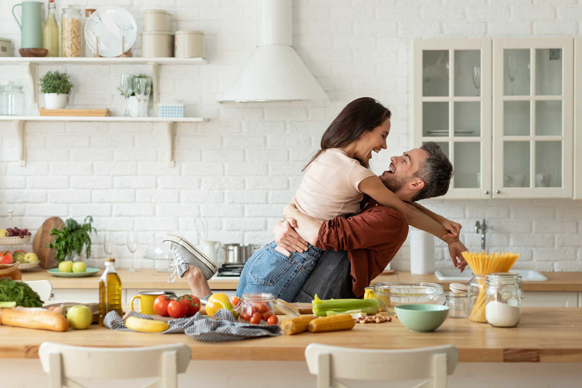Ein junges Paar albert beim Zubereiten von Essen in der Küche rum.