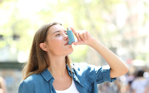 Eine Frau hält einen Asthma-Inhalator.