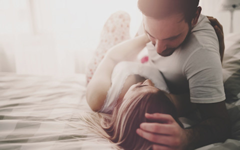 Ein verliebtes Paar liegt zusammen auf dem Bett.