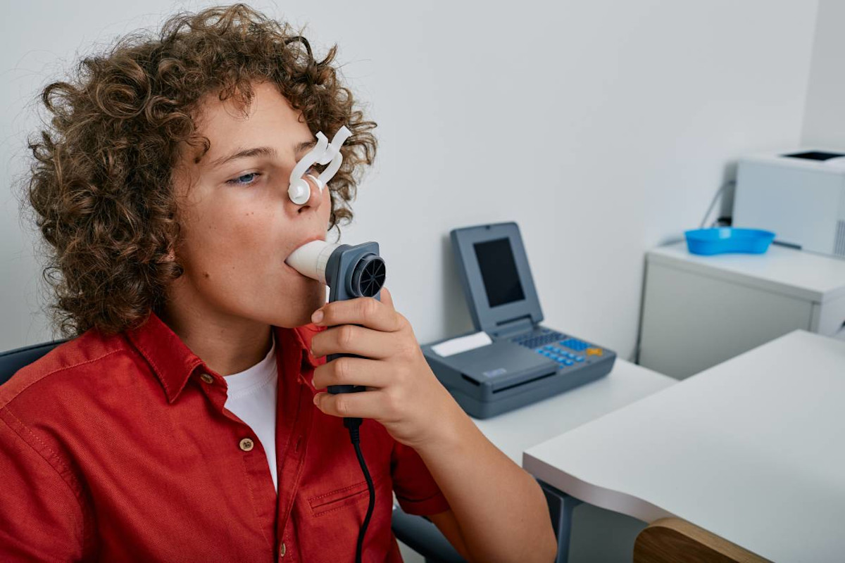 Ein Junge macht in einer Arztpraxis einen Lungenfunktionstest mittels Spirometrie.
