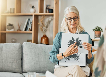 Psychologin sitzt auf Sofa und zeigt einen Rohrschachtest.