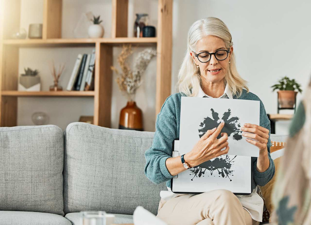 Psychologin sitzt auf Sofa und zeigt einen Rohrschachtest.