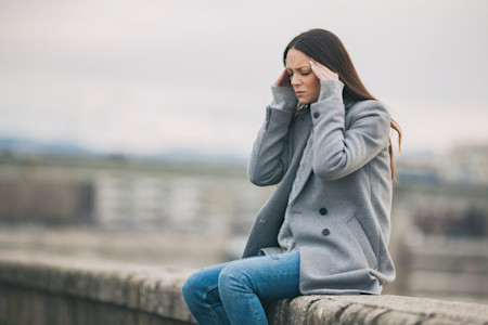 Junge Frau hat Kopfschmerzen durch Wetterumschwung.
