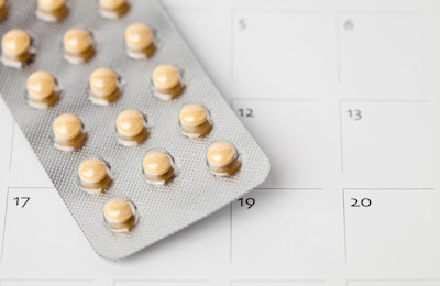 Tablettenblister mit Antibabypille auf Kalenderblatt.