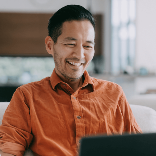 Person in a chair smiling at a laptop screen