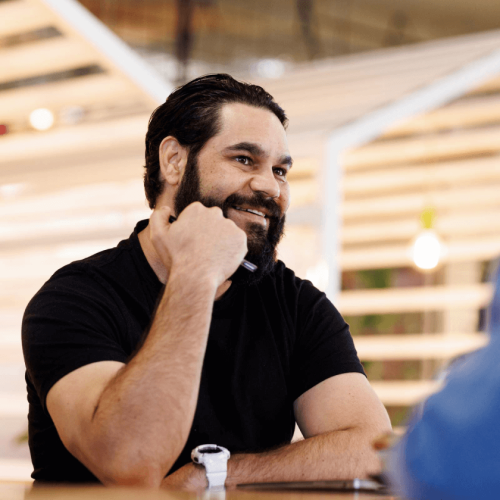 Aboriginal Australian man at meeting with Indigenous colleagues in creative modern workspace.