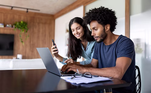 Couple at home paying bills online using a laptop