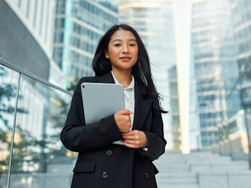 A woman holding a tablet and looking at the camera.