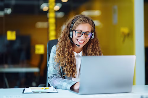 Operador de ventas com headset trabalhando em uma linha de suporte em um escritório moderno.