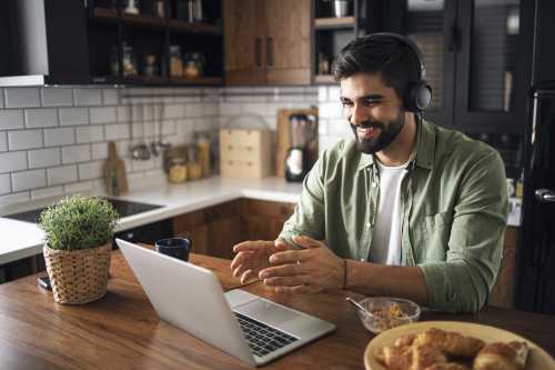 Un joven trabaja desde su laptop en su cocina.