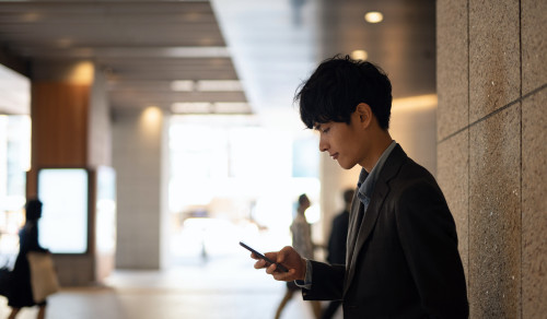 Young businessman looking at smart phone on pedestrian walkway