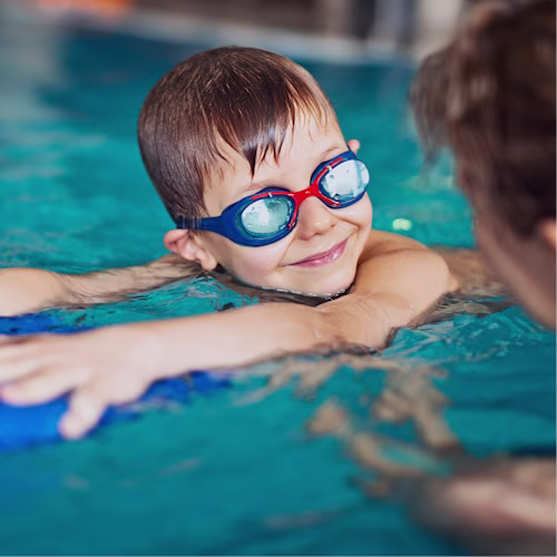 A young boy taking swim lessons in the pool with an instructor