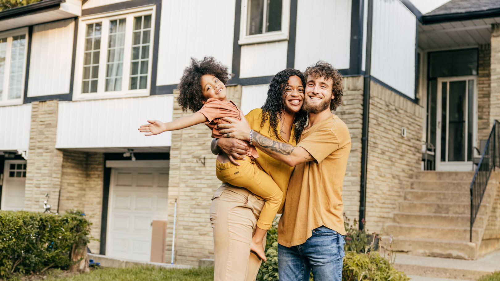 Familia abrazándose frente a una casa