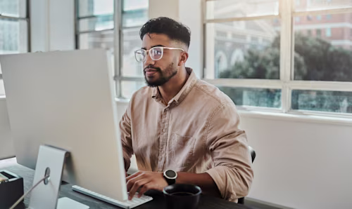 Empresario del sector tecnológico trabajando en el ordenador de la oficina en proyectos de aplicaciones digitales, desarrollo de software o diseño UX/UI de sitios web. 