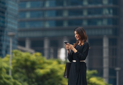 woman in a black dress uses a phone